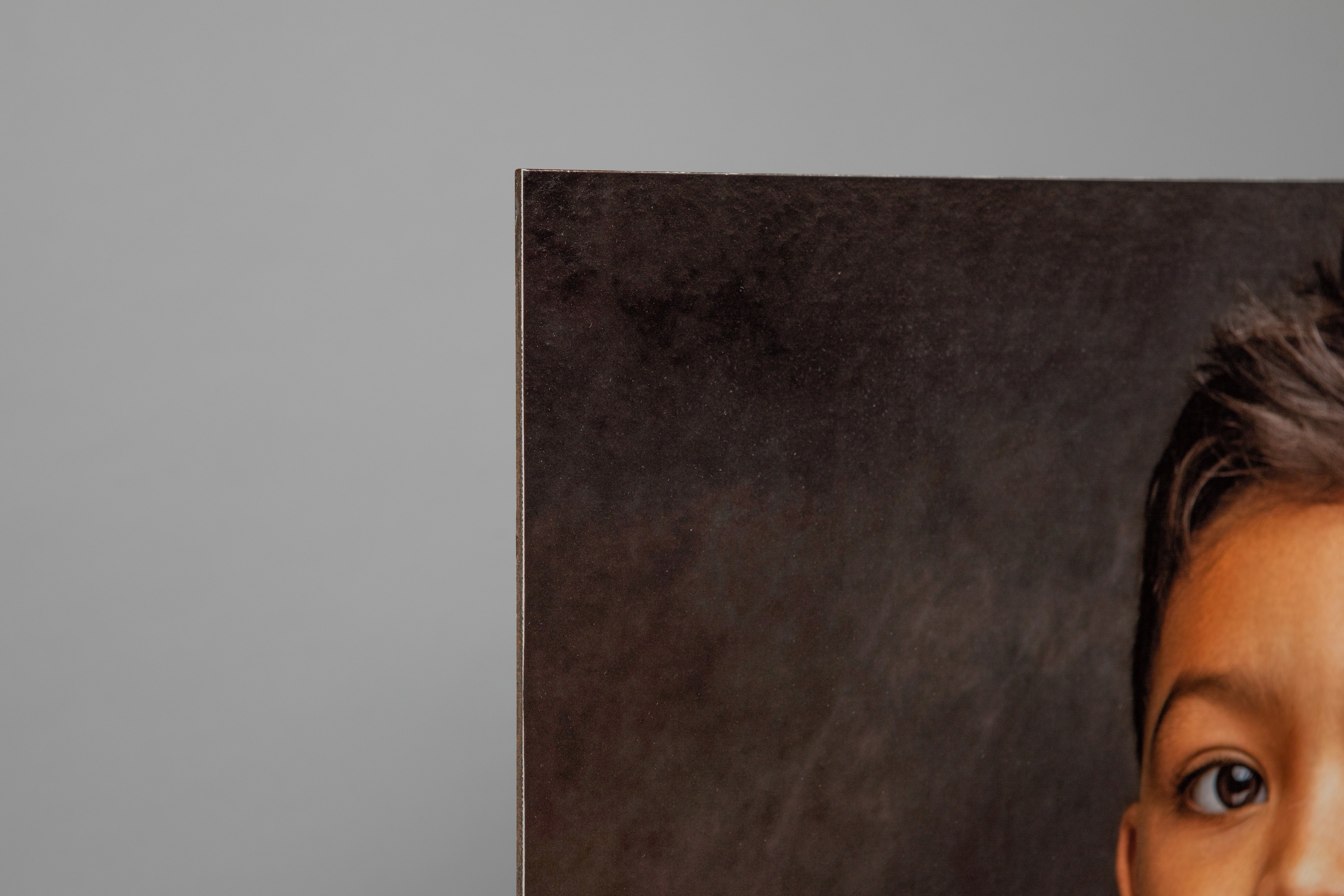 Close-up corner detail of a Portrait Canvas mounted on Masonite over a gray background, print features a formal, professional studio portrait