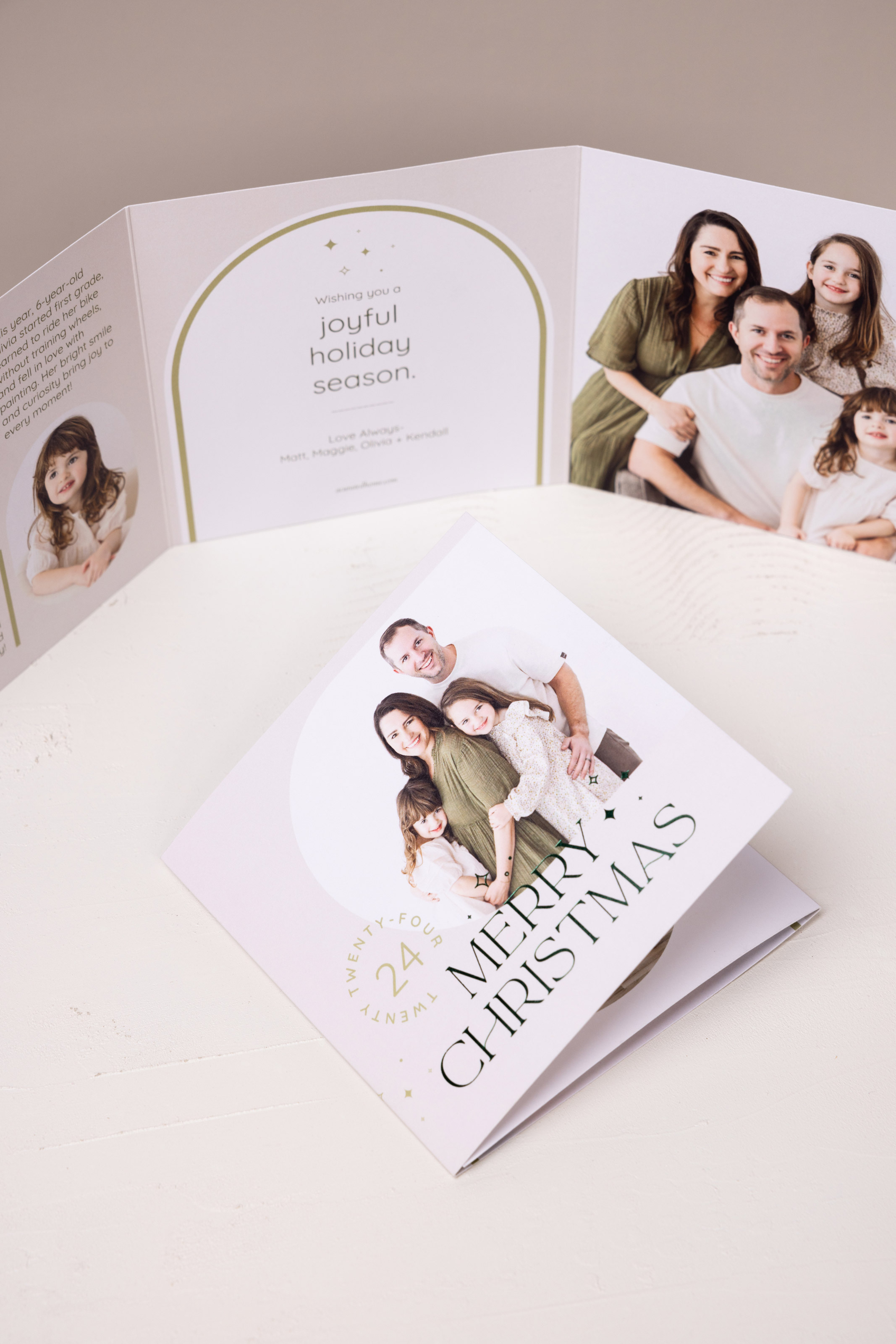 Family portraits printed on 5×5 Trifold Card with everygreen foil-pressed "Merry Christmas" design on a cream surface