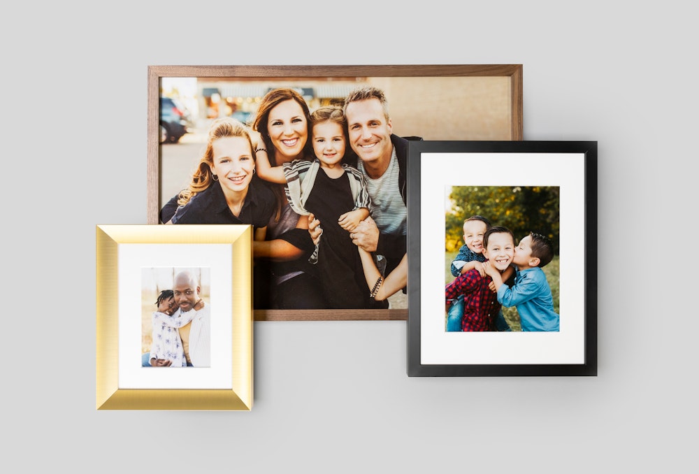 Multiple framed prints of family photos styled on a gray backdrop