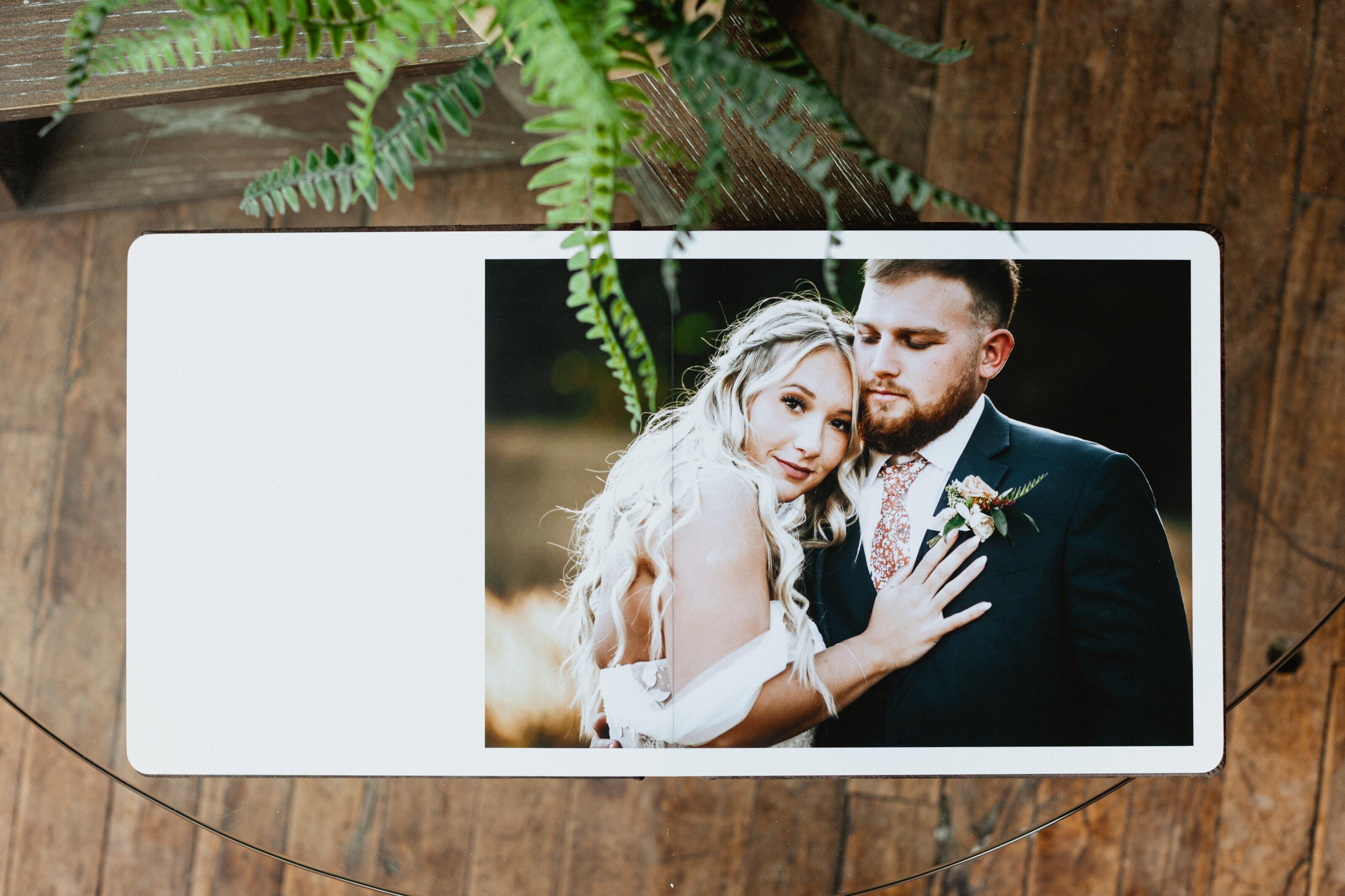 Open wedding photo album showing a flush mount lay-flat spread with a bride and groom portrait printed edge-to-edge on thick insert boards.