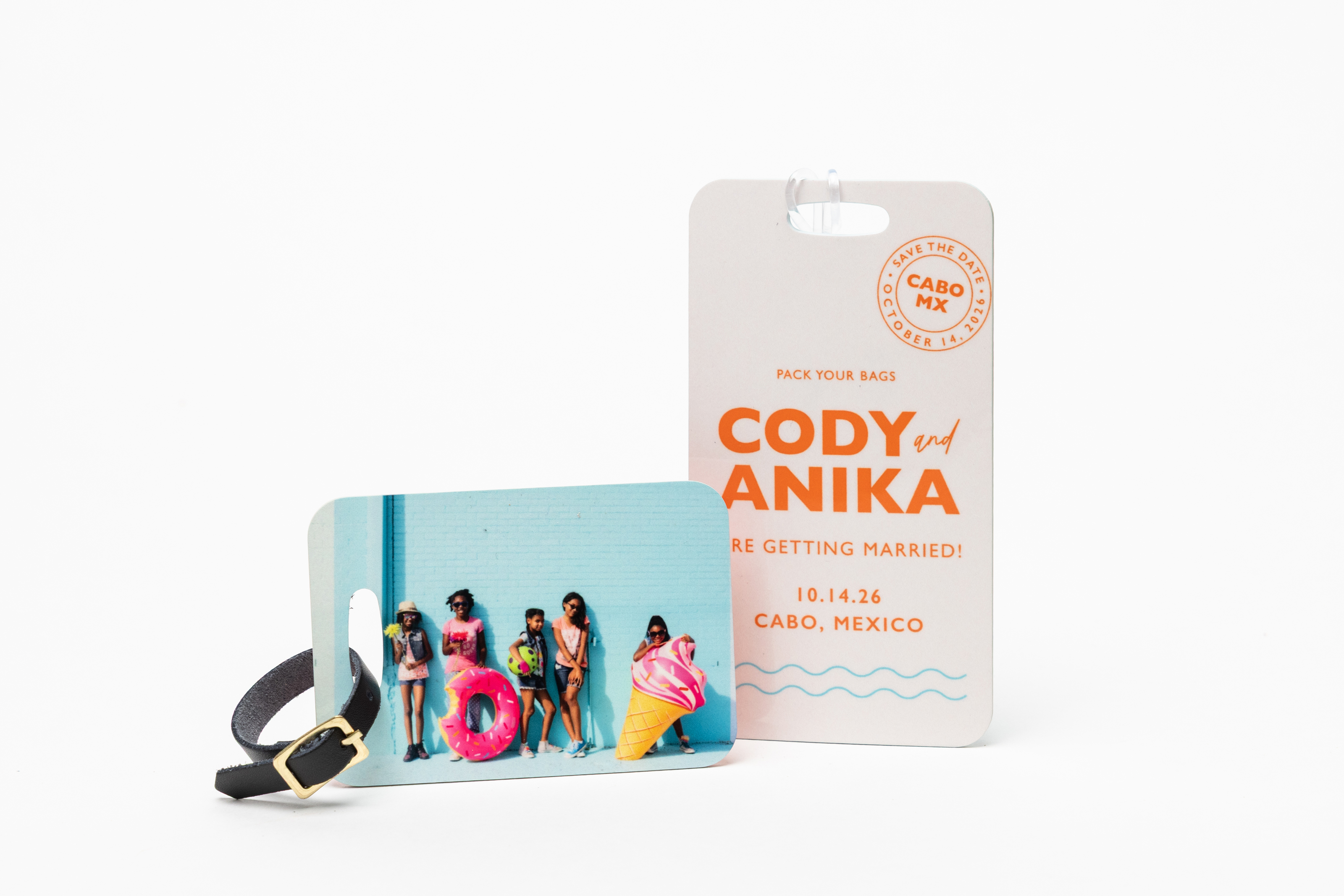 Colorful children's portrait printed on a small Bag Tag with a black leather strap, and a destination wedding design on a large Bag Tag with a clear plastic strap, standing on a white background.