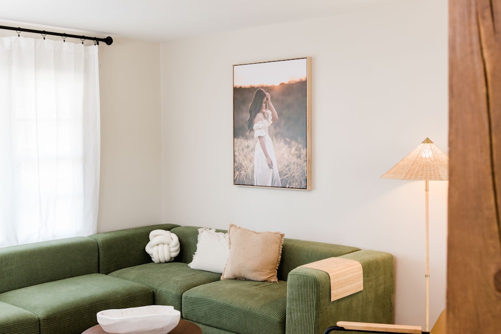 Portrait in a float frame hung above a green couch.