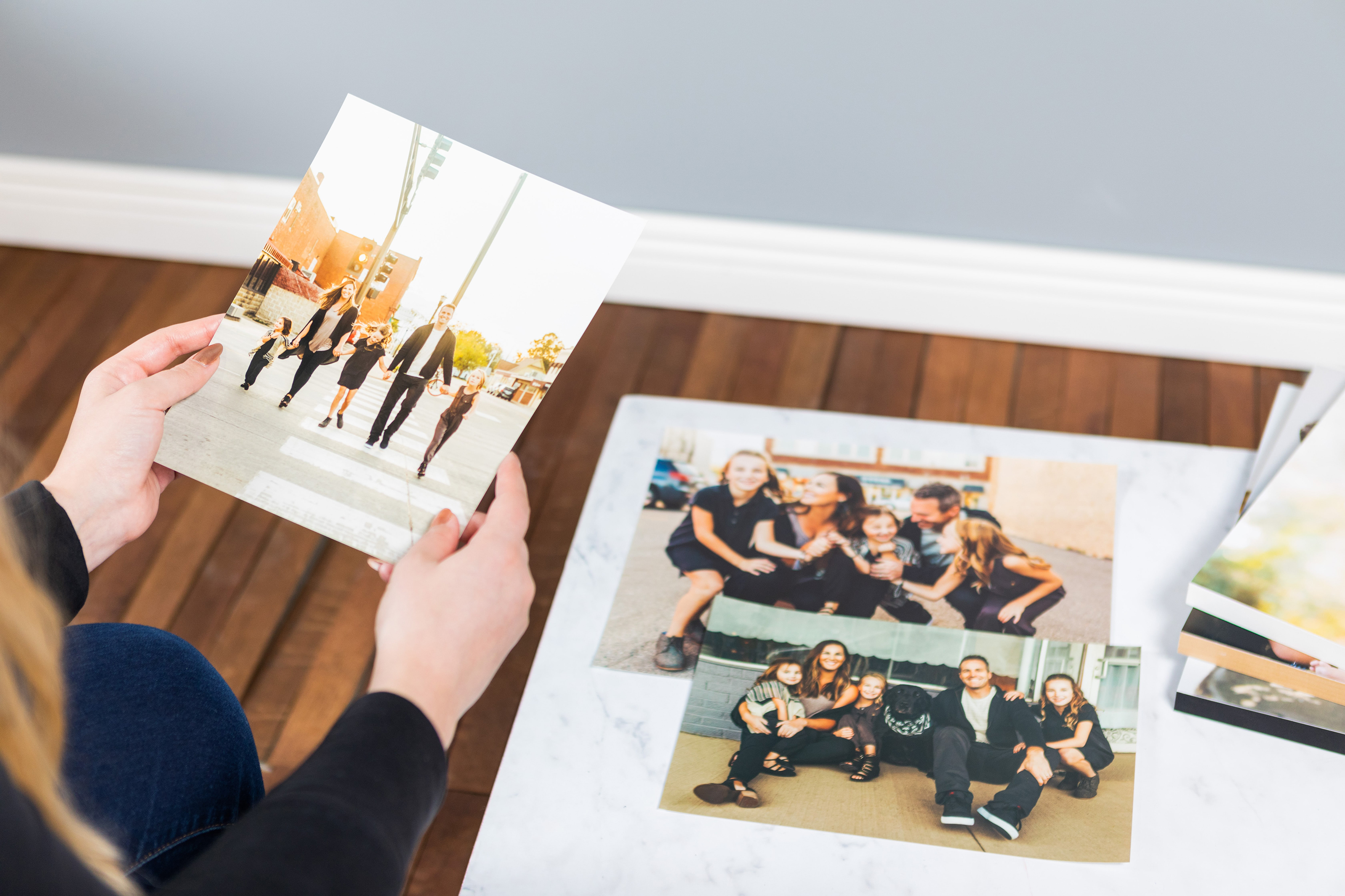 pro quality 5x7 photo print held by a woman above a table showing more high-quality photo printing examples