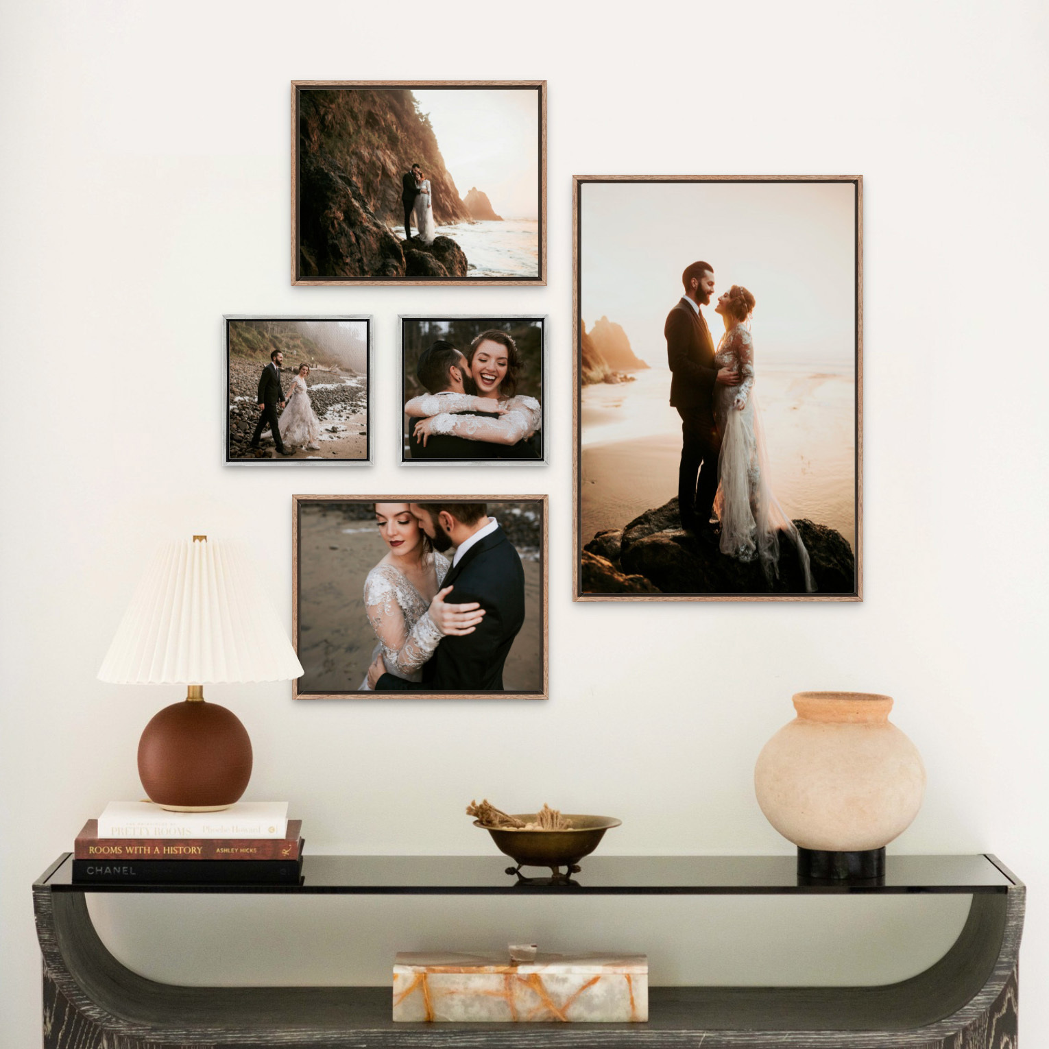 Wedding portraits on a beach at sunset featured in five Float Frames of various sizes on a wall above a side table with a lamp, books, and other decor.