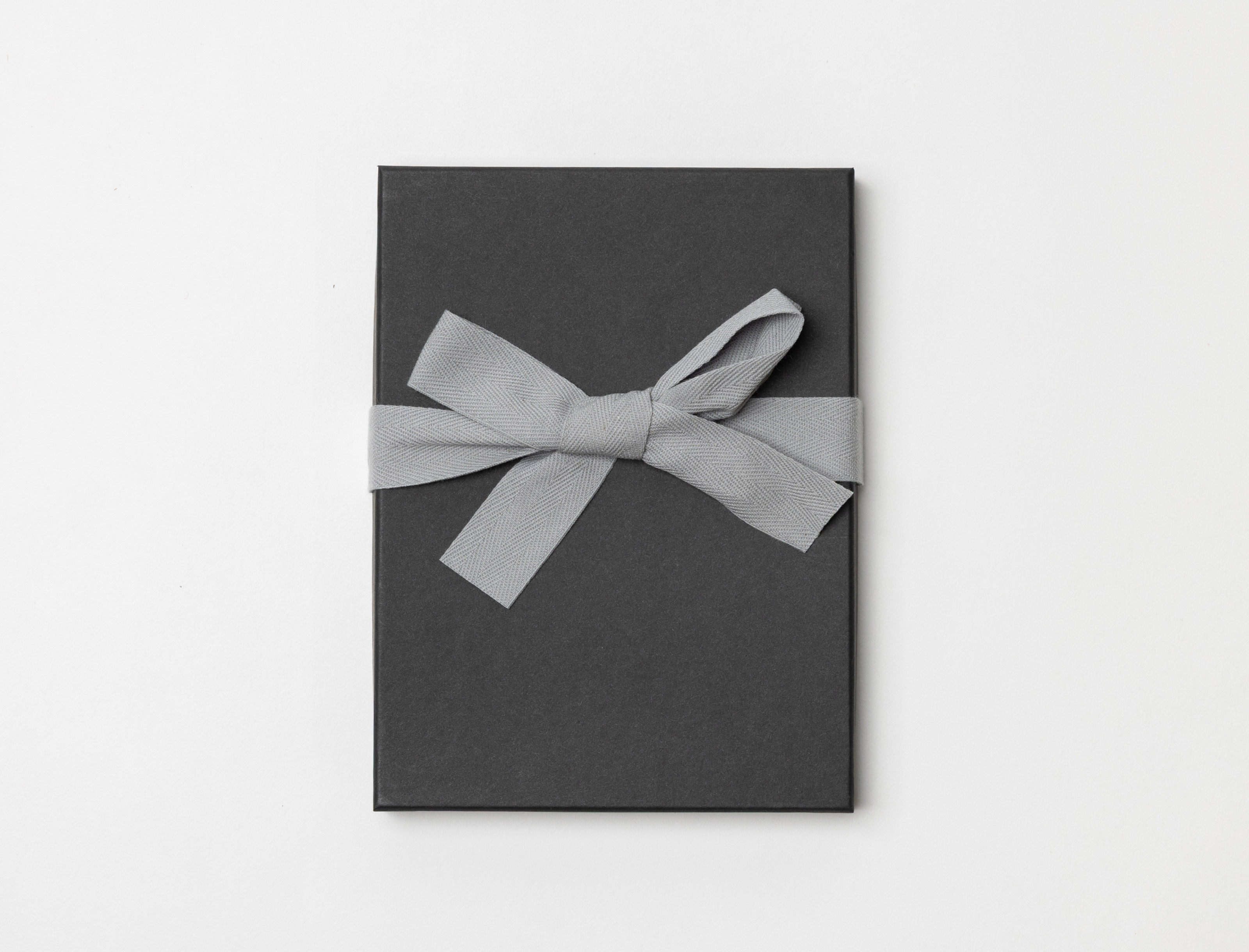 Charcoal Premium Packaging box with a gray ribbon tied in a bow on a light gray background