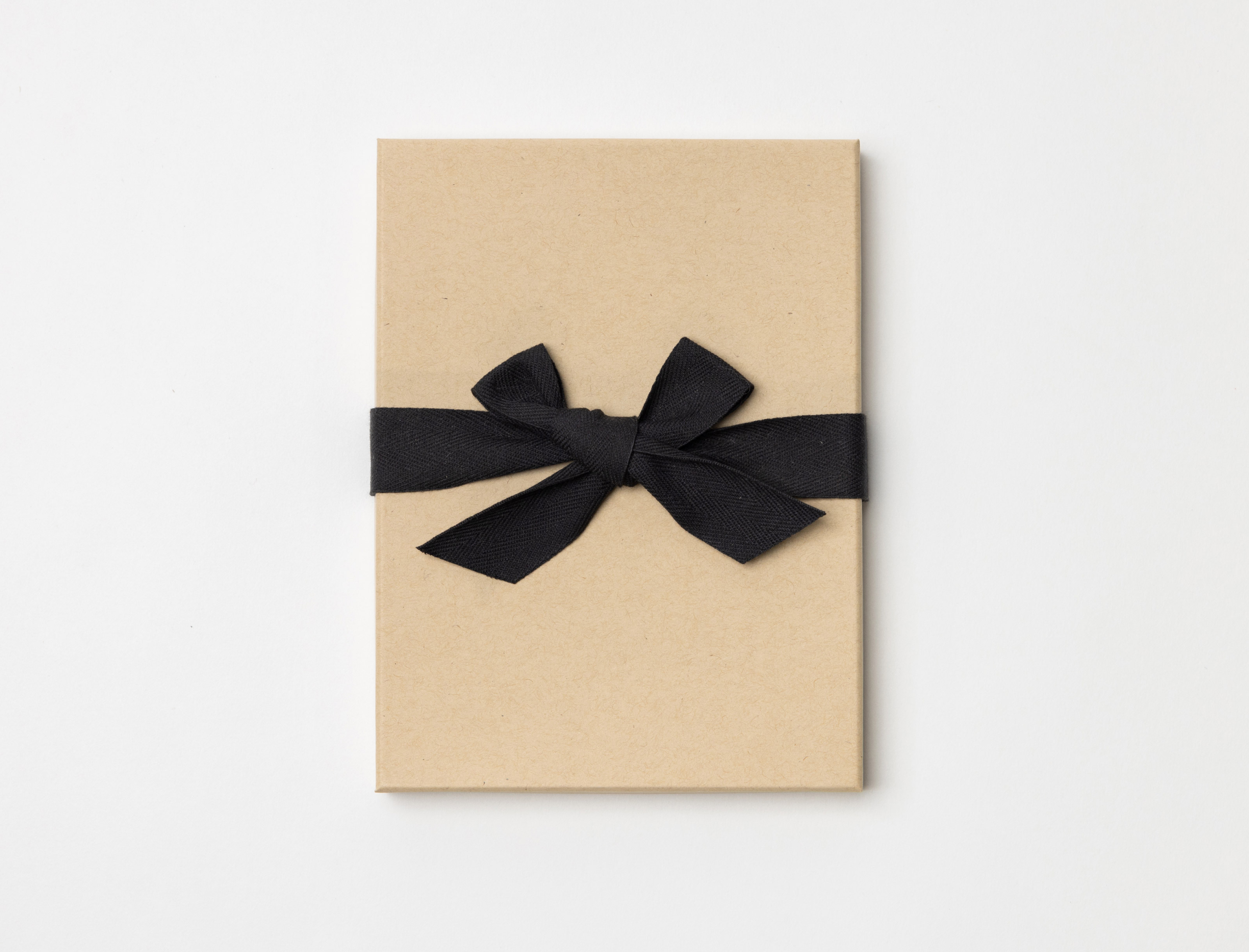 Kraft Premium Packaging box with a black ribbon tied in a bow on a light gray background